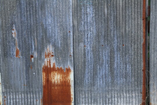 An old and rusty zinc sheet wall. Vintage style metal sheet roof texture. Pattern of old metal sheet. Rusting metal or siding. Corrosion of galvanized. Background and texture in retro concept