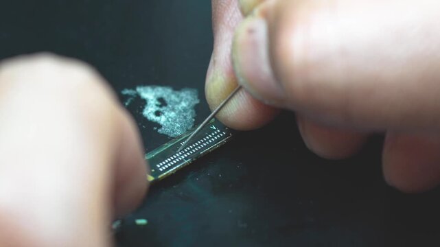 Technician cleaning a circuit board connector with precision tools close up workbench
