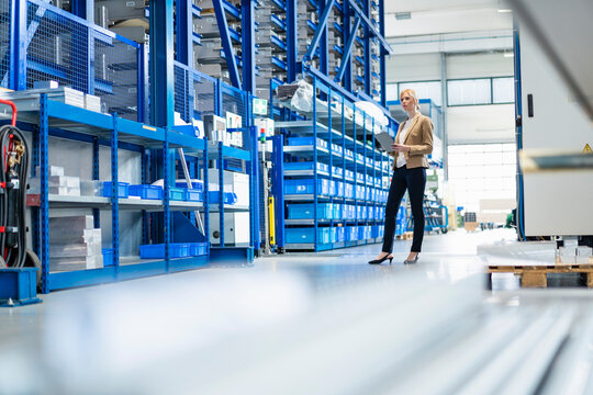 Businesswoman with tablet in factory storehouse