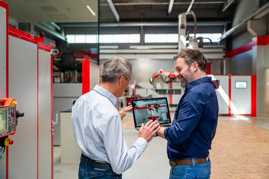 Colleagues discussing industrial automation on a laptop in a factory