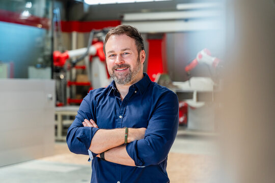 Smiling engineer with arms crossed in modern automated factory