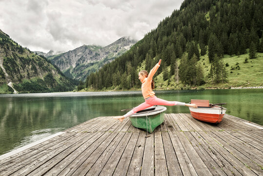 Cheerful girl jumping and doing splits in air over jetty