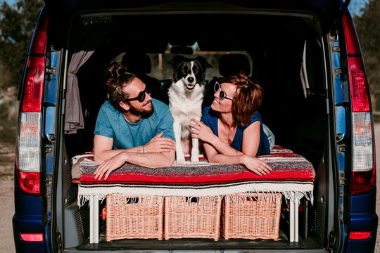 Relaxed couple with dog lying in the boot of a minivan