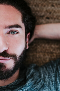 Close-up of handsome man with hands behind head lying on floor at home
