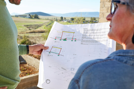 Architect and builder discussing house plans at building site
