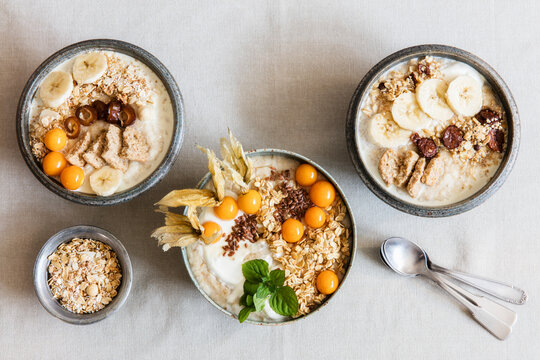 Three bowls of porridge with oats, flax seed, winter cherries and bananas