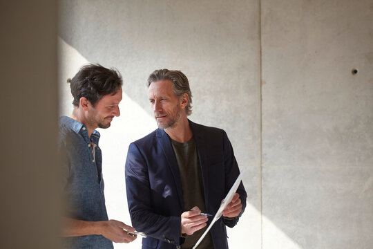 Two men on construction site discussing document