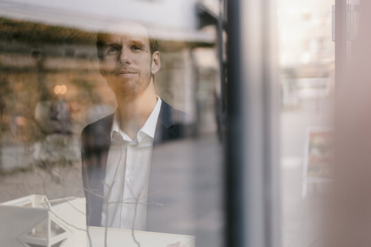 Portrait of businessman with architectural model looking out of window