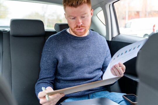 Entrepreneur reading document in the back seat of a car