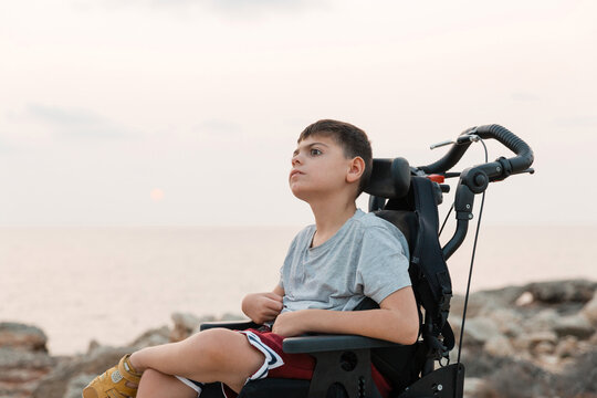 Wheelchair user looking at the sea during sunset in Menorca