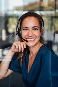 Happy businesswoman wearing headset sitting in soundproof cabin