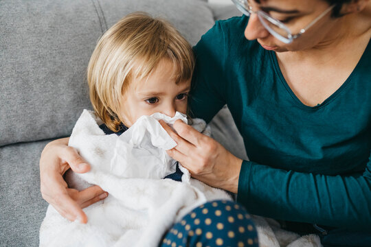 Mother blowing little daughter's nose