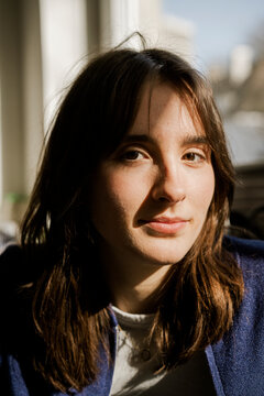 Portrait of young Gen Z woman at home with sun and shadow on face