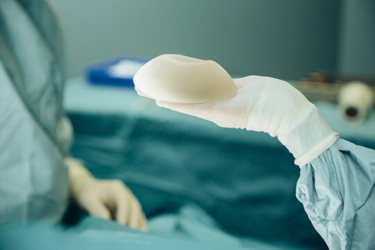 Hand holding up silicone implant during surgery