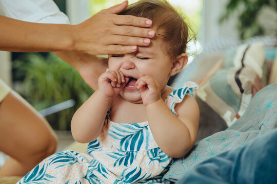 Mother taking temperature of her crying baby girl