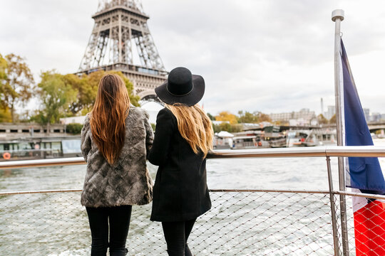 Paris, France, two tourists taking a cruise on Seine River with Eiffel Tower in the background