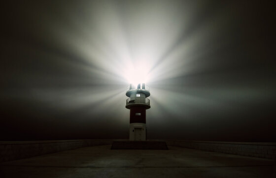 Spain, Carino, beaming lighthouse in a foggy night
