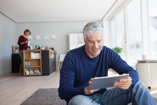 Man sitting on the floor at home using digital tablet