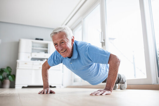 Portrait of senior man doing pushups at home
