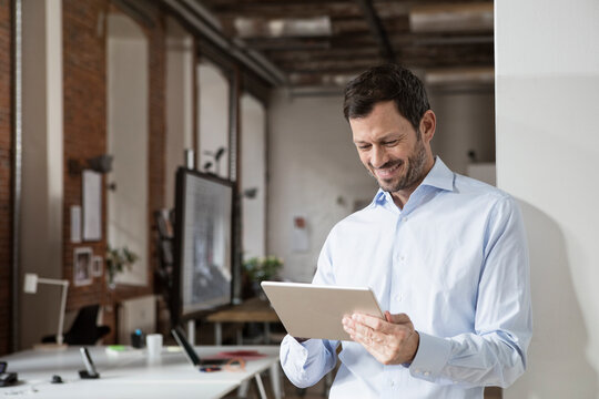 Smiling businessman using tablet in office