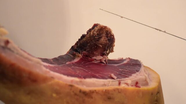 Hand-sliced prosciutto being prepared with precision by expert using a sharp knife