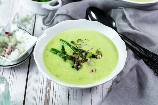Fresh creamy asparagus soup with radishes in a white bowl