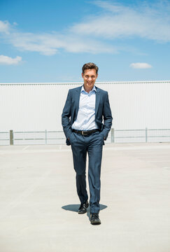 Smiling business man walking on parking level