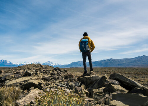 Hiker standing on rock looking at mountain range in Patagonia