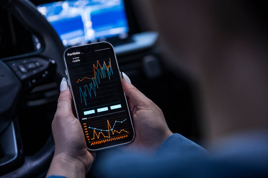 Checking financial portfolio on smartphone app inside car at night