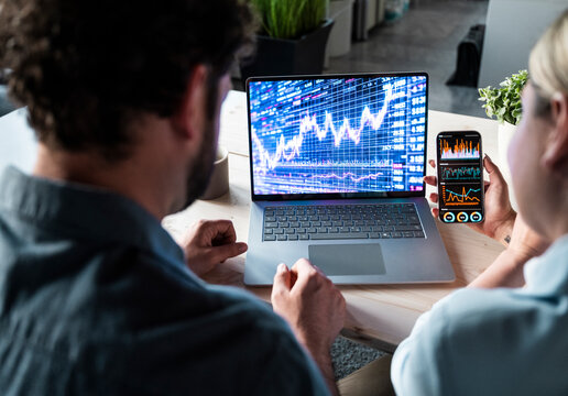 Investors analyzing financial stock market data on laptop screen