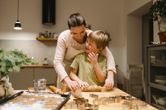Happy son making ginger cookies with mother in kitchen