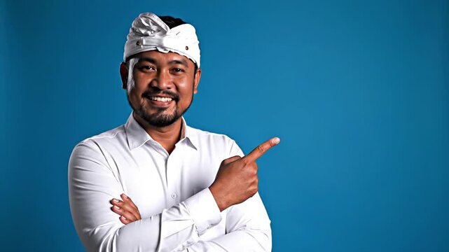 Friendly Balinese man in traditional udeng pointing, ideal for digital marketing, business presentations, and educational content. Engaging gesture for audience attention, brand promotion, and...