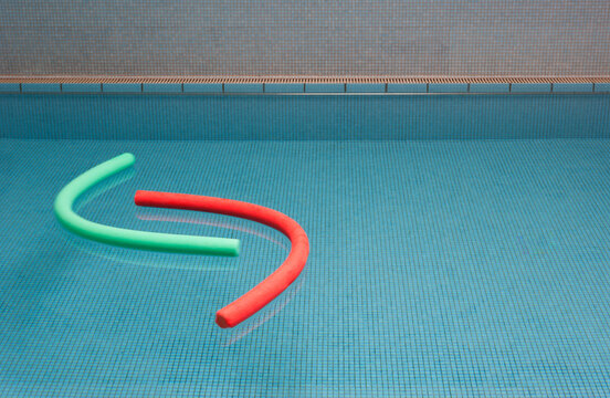 Aqua noodles floating on water of indoor swimming pool