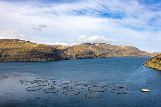 Salmon fish farm in ocean water near mountain at the coast of Streymy Island, Faroe Islands