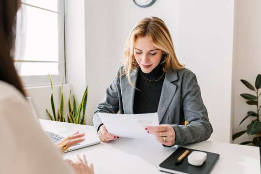 Smiling HR manager reading resume at desk