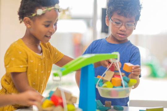 Boy and girl playing with toy scales in kindergarten