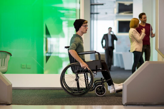 Young man in wheelchair listening to music in office
