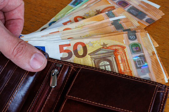 Hand taking a 50 Euro banknote from wallet, cost of living, wages, or inflation concept.