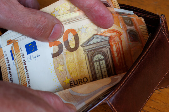 Hand taking a 50 Euro banknote from wallet, cost of living, wages, or inflation concept.