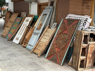 Vintage wooden doors displayed outside antique shop with intricate designs and weathered textures © dvoevnore