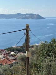 Telephone pole overlooking serene coastal village with distant mountain backdrop © dvoevnore