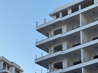 Modern apartment building exterior against clear blue sky, suitable as architectural background © dvoevnore