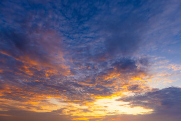 Fototapeta premium Dramatic Golden Sunset Clouds Filling the Evening Sky,A breathtaking view of a vibrant sunset sky filled with dramatic, textured clouds illuminated by warm golden and purple light, creating a serene.