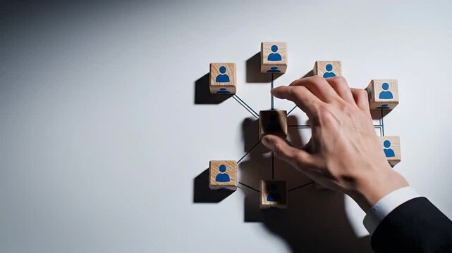 Hand building an interconnected organizational network system with wooden blocks, representing team building, talent management, and strategic growth for improved collaboration and efficient human...