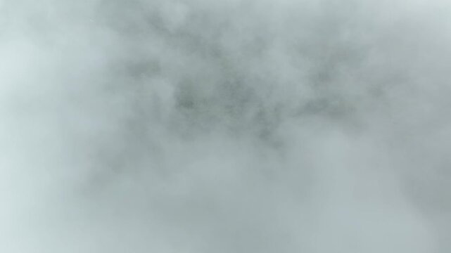 Drone flying through clouds over a green forest