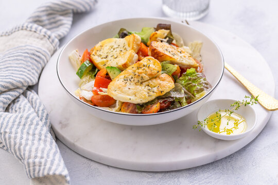 Fresh halloumi cheese salad, grilled halloumi slices with mixed greens, cherry tomatoes and cucumber