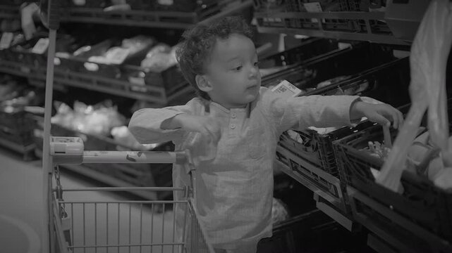 Child pushing small shopping cart in supermarket produce aisle