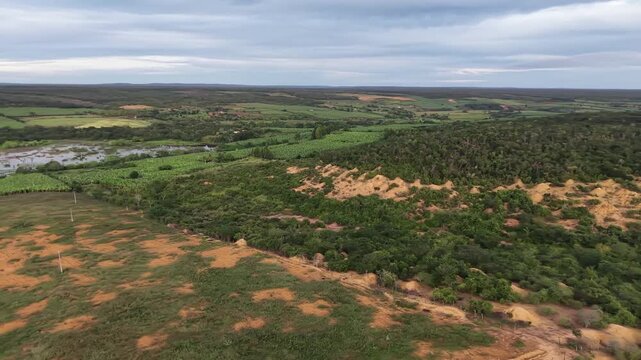 V&iacute;deo de drone mostrando o leito do Rio Utinga com &aacute;reas alagadas, cercado por vegeta&ccedil;&atilde;o de mata nativa preservada em contraste com uma vasta planta&ccedil;&atilde;o de banana, Chapada Diamantina, Bahia, Brasil.