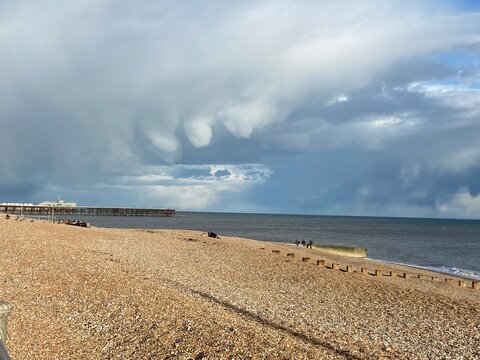 Rare mammatus cloud formation hanging over the sea before a thunderstorm. Dramatic storm clouds with unusual pouch-shaped formations above a beach, creating an atmospheric weather background with copy