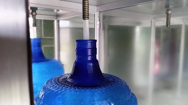 The process of refilling clean mineral drinking water at the filling depot.